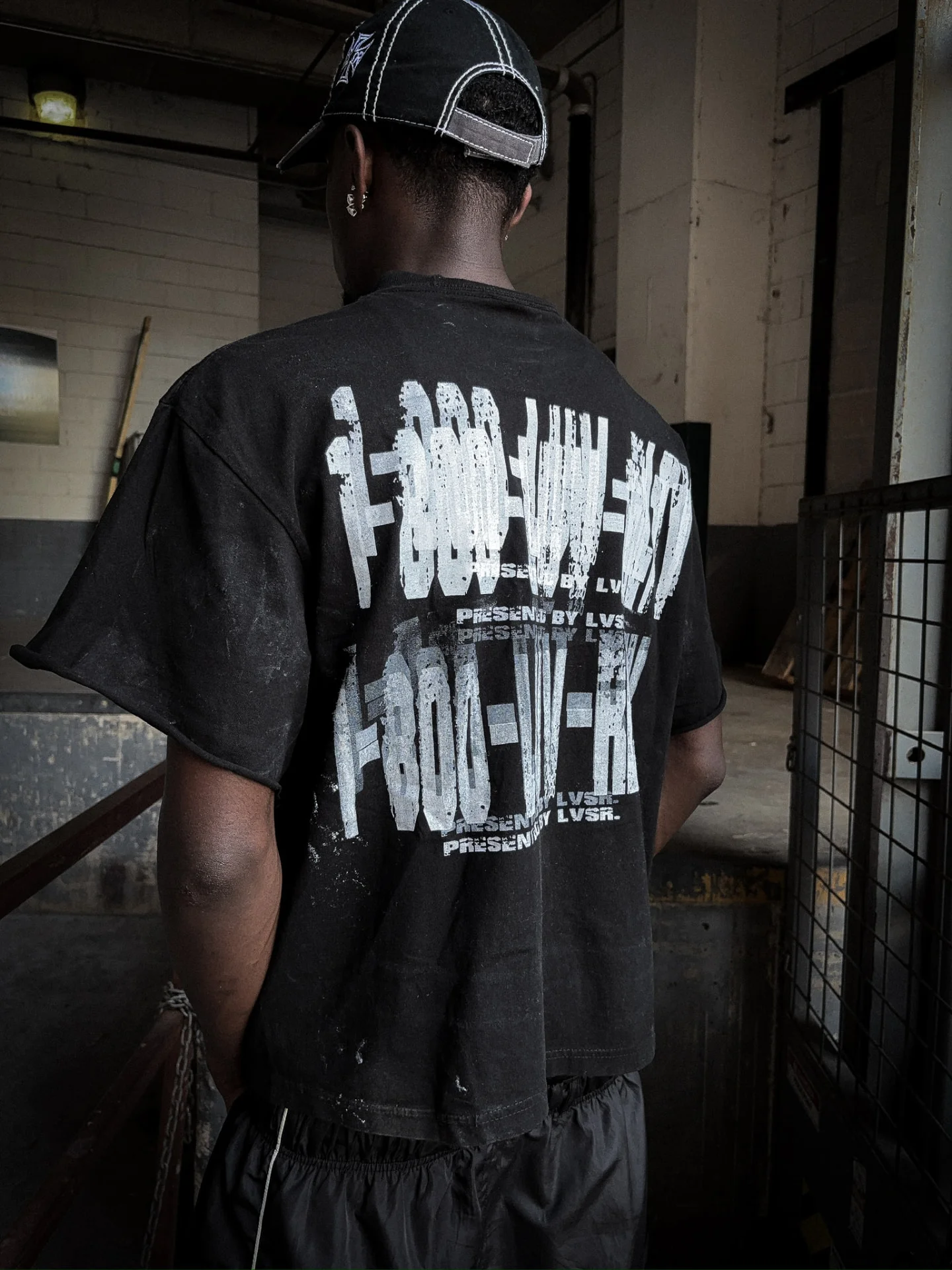 Model from behind in black LVSR Human Race tee, back print detail