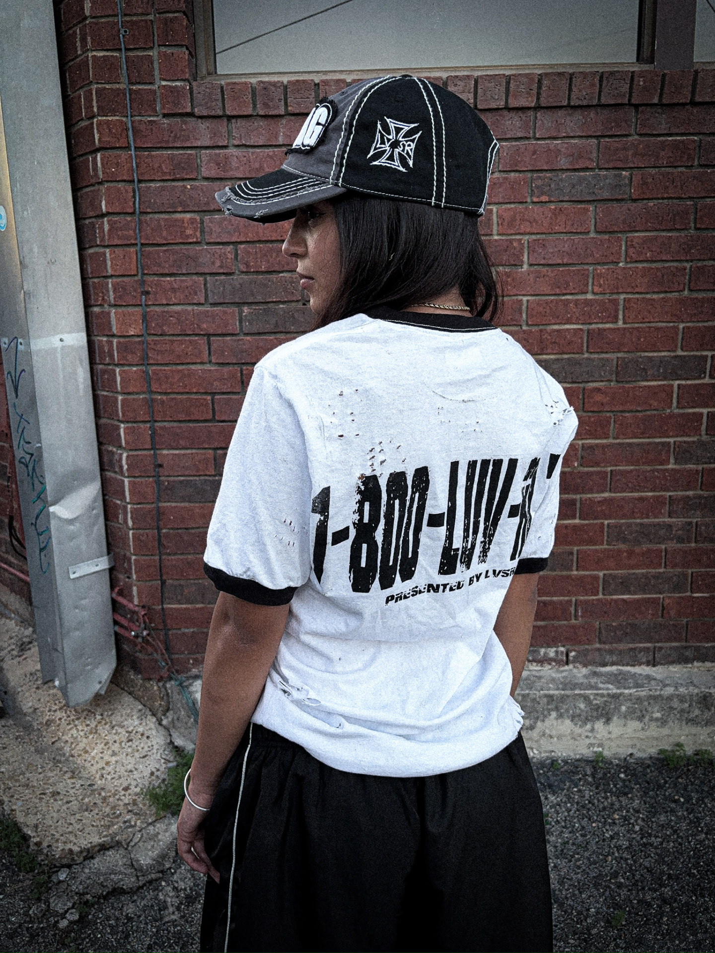 Model in white LVSR Nothing Here Is Worth Dying For tee and black shorts, side profile